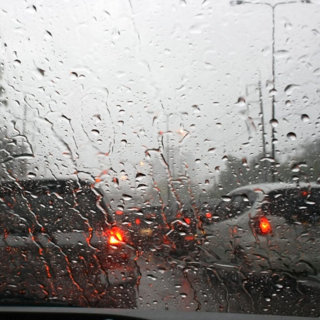 Road view through car window with rain drops, Driving in rain.